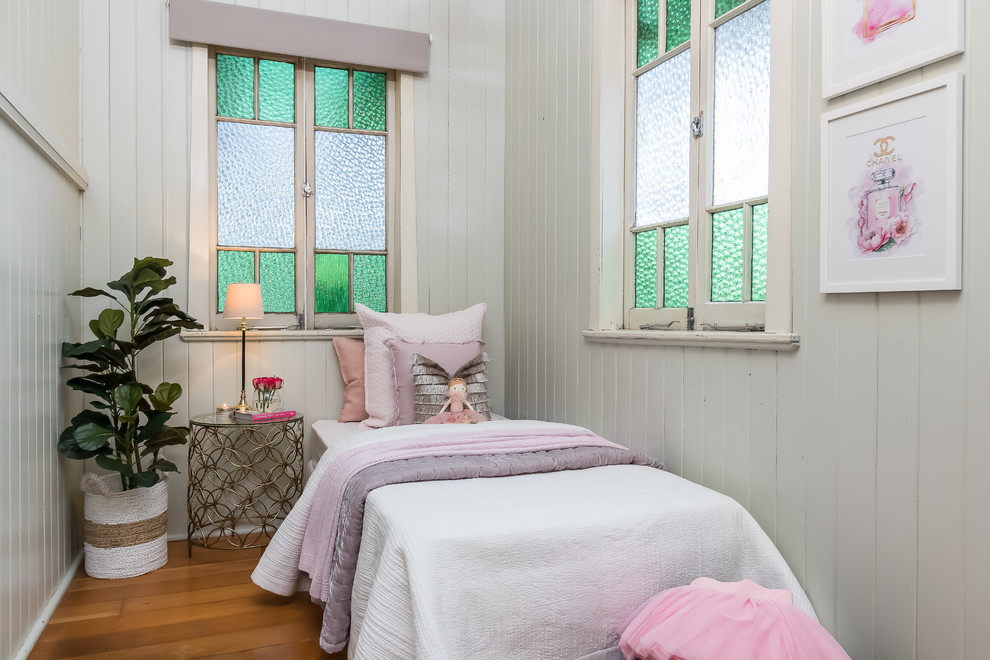 This is an example of a country kids' bedroom for girls in Brisbane with grey walls, medium hardwood flooring and brown floors.