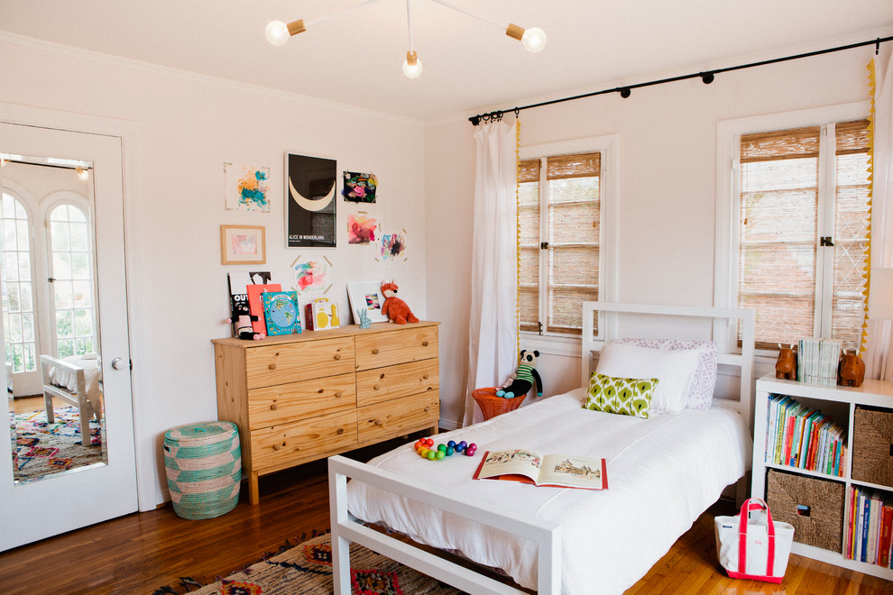 Medium sized mediterranean gender neutral children’s room in New York with pink walls and dark hardwood flooring.