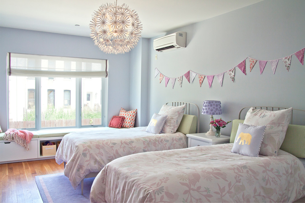 Medium sized traditional children’s room for girls in New York with blue walls, medium hardwood flooring and brown floors.