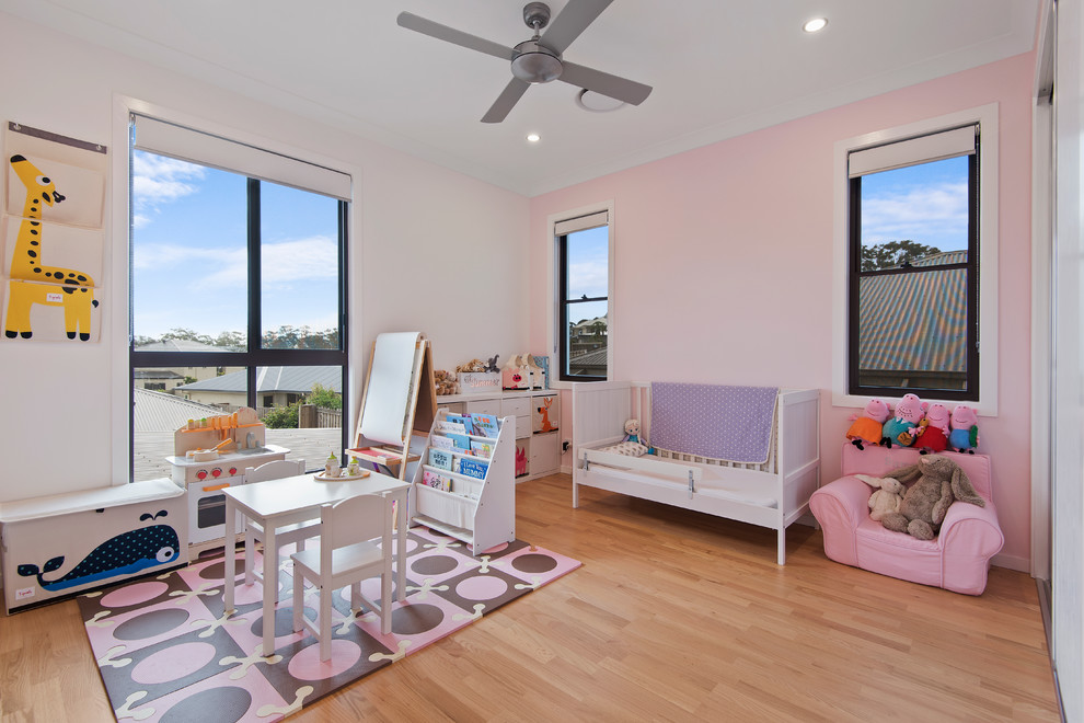 Inspiration for a medium sized contemporary toddler’s room for girls in Brisbane with pink walls and light hardwood flooring.