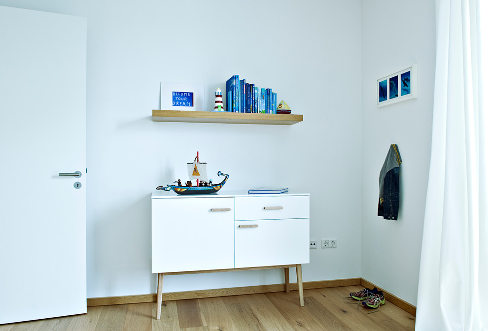 Immagine di una cameretta da bambino da 4 a 10 anni contemporanea di medie dimensioni con pareti bianche e pavimento in legno massello medio