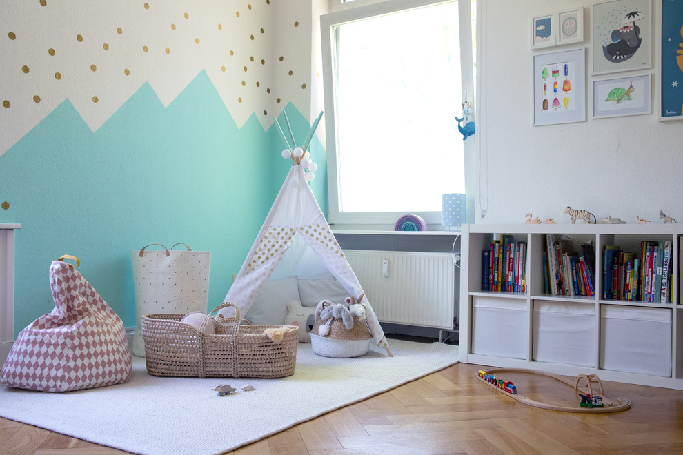 Immagine di una cameretta per bambini da 1 a 3 anni scandinava di medie dimensioni con pareti bianche, pavimento in legno massello medio e pavimento beige