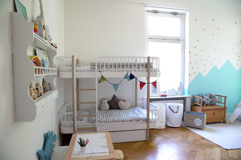 На фото: детская среднего размера в скандинавском стиле с спальным местом, белыми стенами, паркетным полом среднего тона и бежевым полом для ребенка от 1 до 3 лет, мальчика с