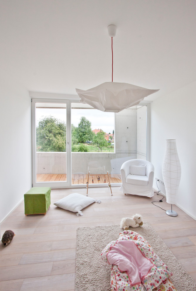 Ispirazione per una cameretta per bambini da 1 a 3 anni design di medie dimensioni con pareti bianche e parquet chiaro