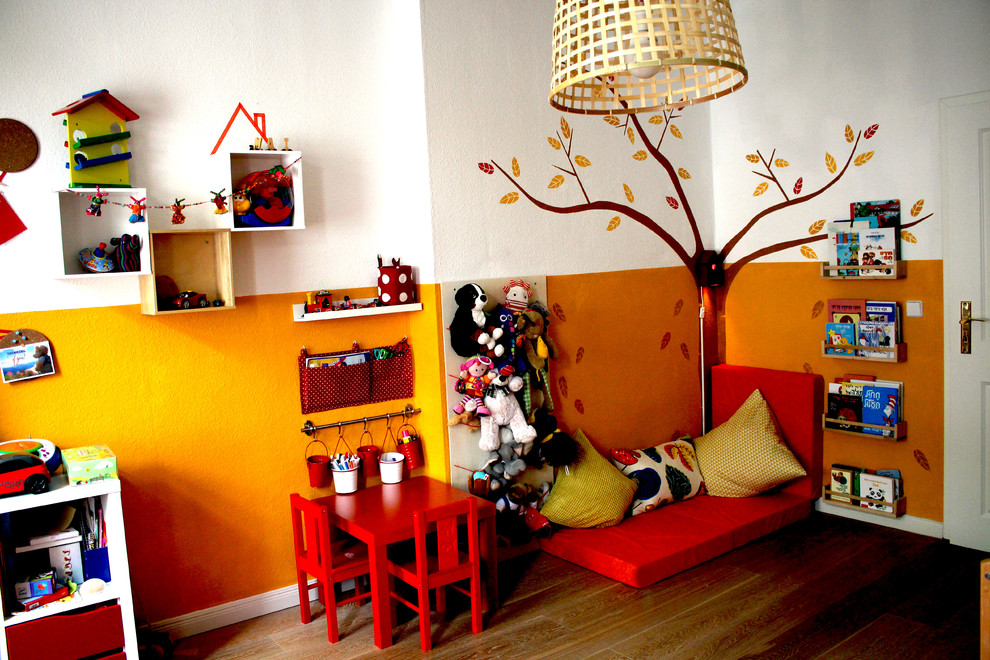 Ispirazione per una cameretta per bambini da 1 a 3 anni minimal di medie dimensioni con pareti multicolore, pavimento in laminato e pavimento marrone