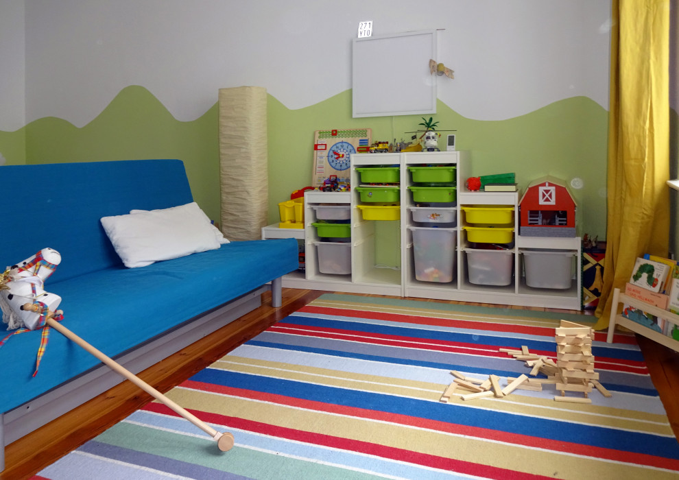 Inredning av ett modernt mellanstort könsneutralt småbarnsrum kombinerat med lekrum, med gröna väggar, mörkt trägolv och brunt golv
