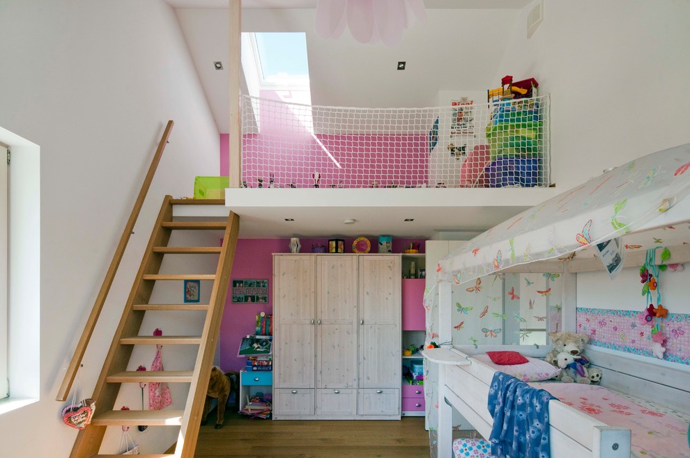 Design ideas for a medium sized contemporary kids' bedroom for girls in Munich with medium hardwood flooring, brown floors and pink walls.