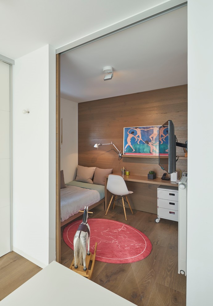 Photo of a contemporary gender neutral kids' bedroom in Berlin with white walls, medium hardwood flooring and brown floors.