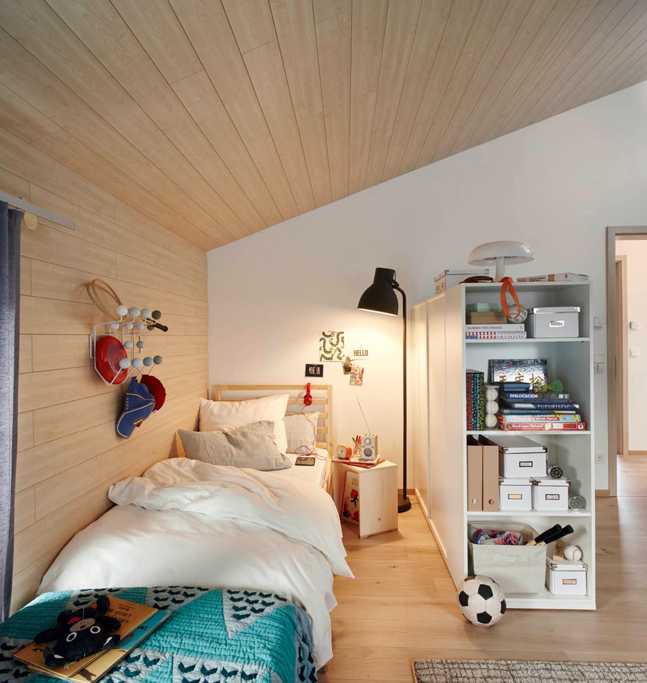 Modern inredning av ett barnrum kombinerat med sovrum, med vita väggar och ljust trägolv