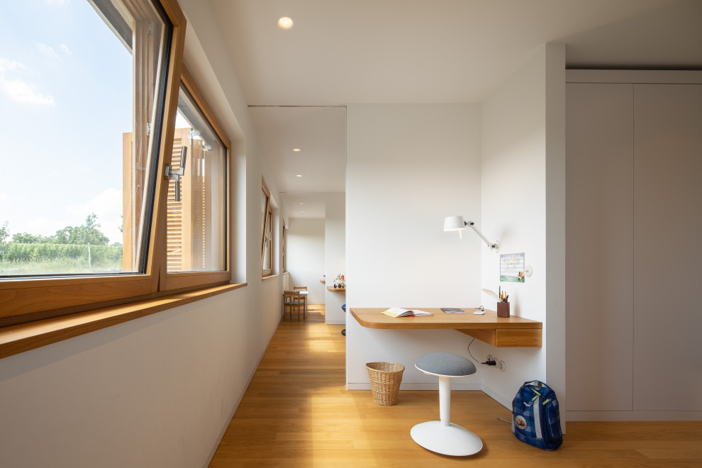 Bild på ett mellanstort funkis könsneutralt tonårsrum kombinerat med skrivbord, med vita väggar, mellanmörkt trägolv och brunt golv