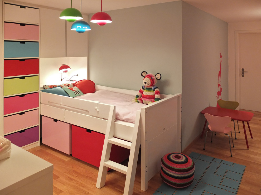 Ispirazione per una cameretta per bambini da 4 a 10 anni minimal di medie dimensioni con pareti grigie e pavimento in legno massello medio
