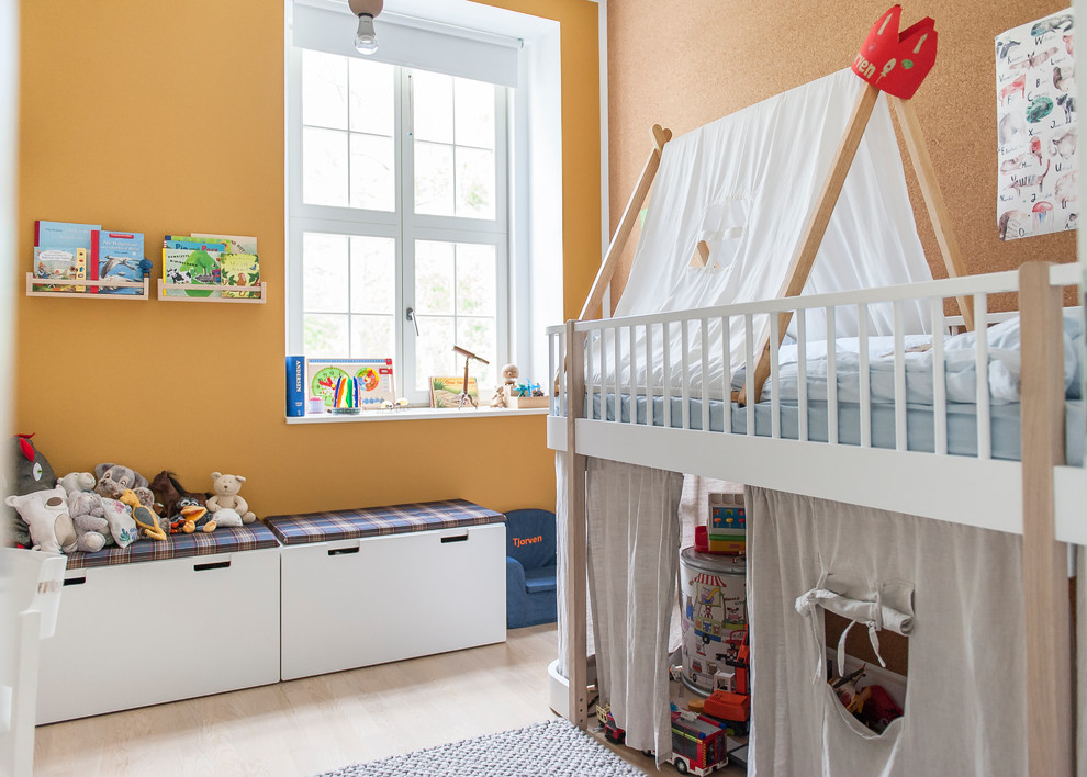 Small contemporary gender neutral children’s room in Berlin with orange walls, light hardwood flooring and beige floors.
