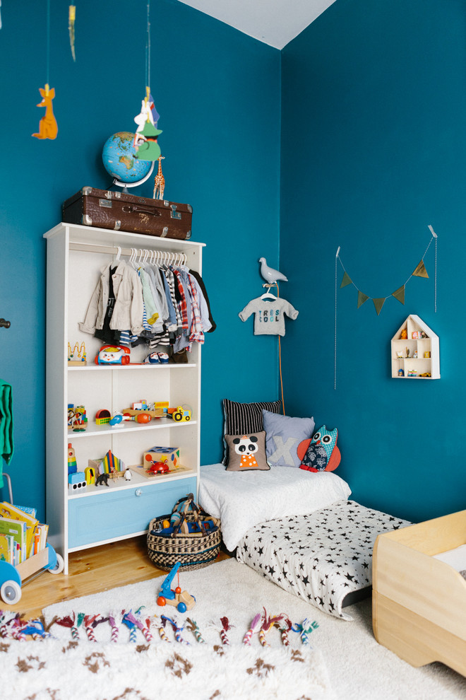 Ejemplo de dormitorio infantil de 4 a 10 años bohemio de tamaño medio con paredes azules y suelo de madera clara