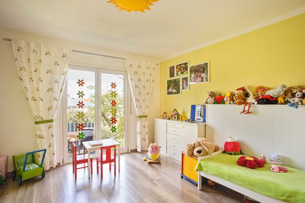 Réalisation d'une grande chambre d'enfant de 4 à 10 ans design avec parquet clair et un mur multicolore.