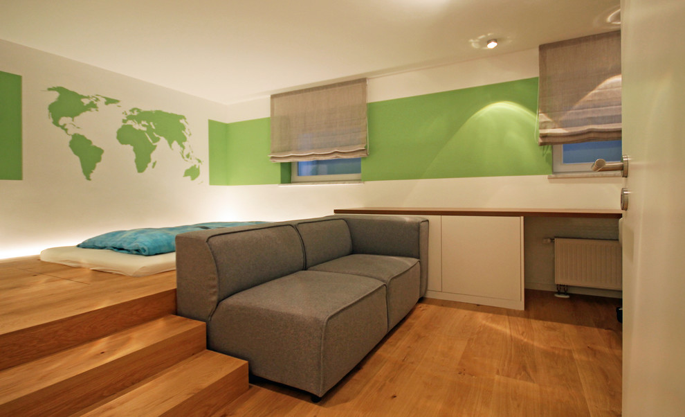 Cette photo montre une grande chambre d'enfant tendance avec un mur vert, parquet clair et un sol marron.