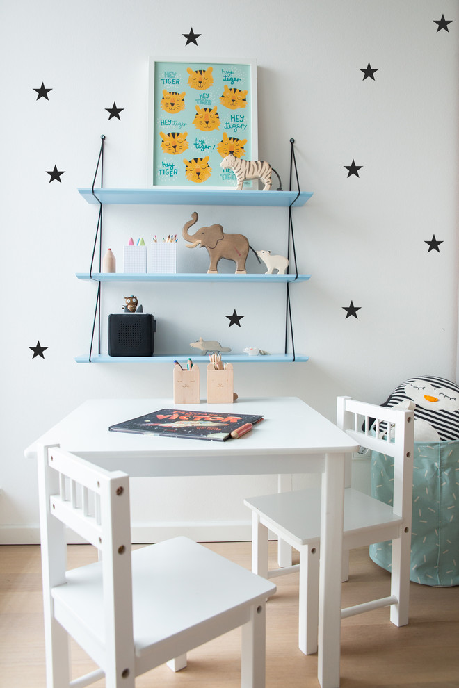 Exemple d'une chambre de garçon de 1 à 3 ans tendance de taille moyenne avec un bureau, un mur blanc, un sol en bois brun et un sol beige.