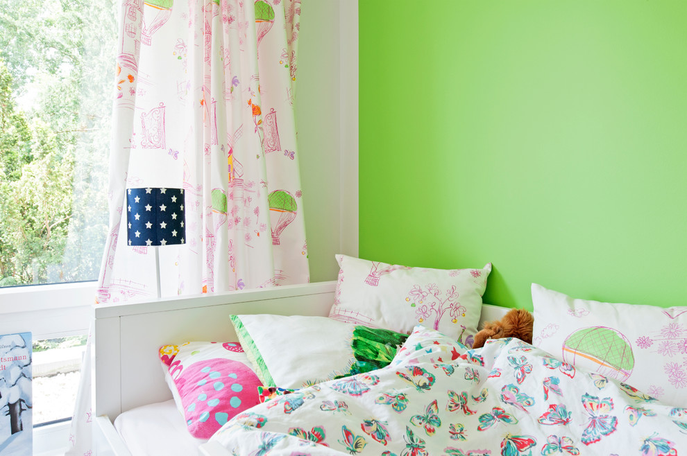 Inspiration for a large contemporary children’s room for girls in Dusseldorf with green walls, light hardwood flooring and brown floors.
