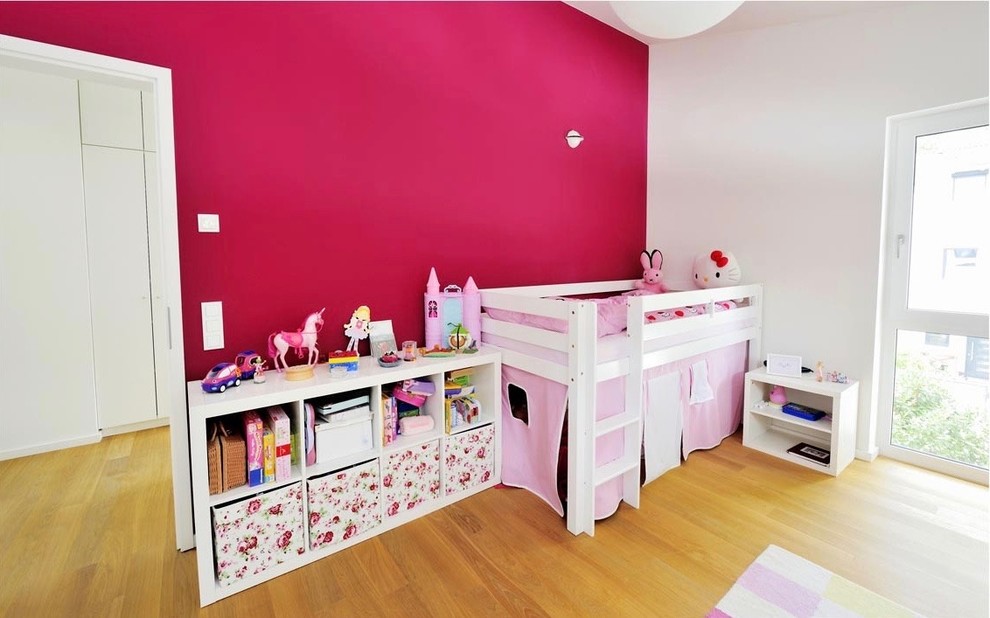 Modern inredning av ett stort flickrum kombinerat med sovrum och för 4-10-åringar, med vita väggar, ljust trägolv och brunt golv