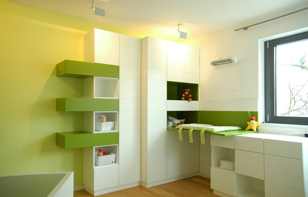 Idéer för stora funkis könsneutrala småbarnsrum kombinerat med sovrum, med gröna väggar, mellanmörkt trägolv och brunt golv