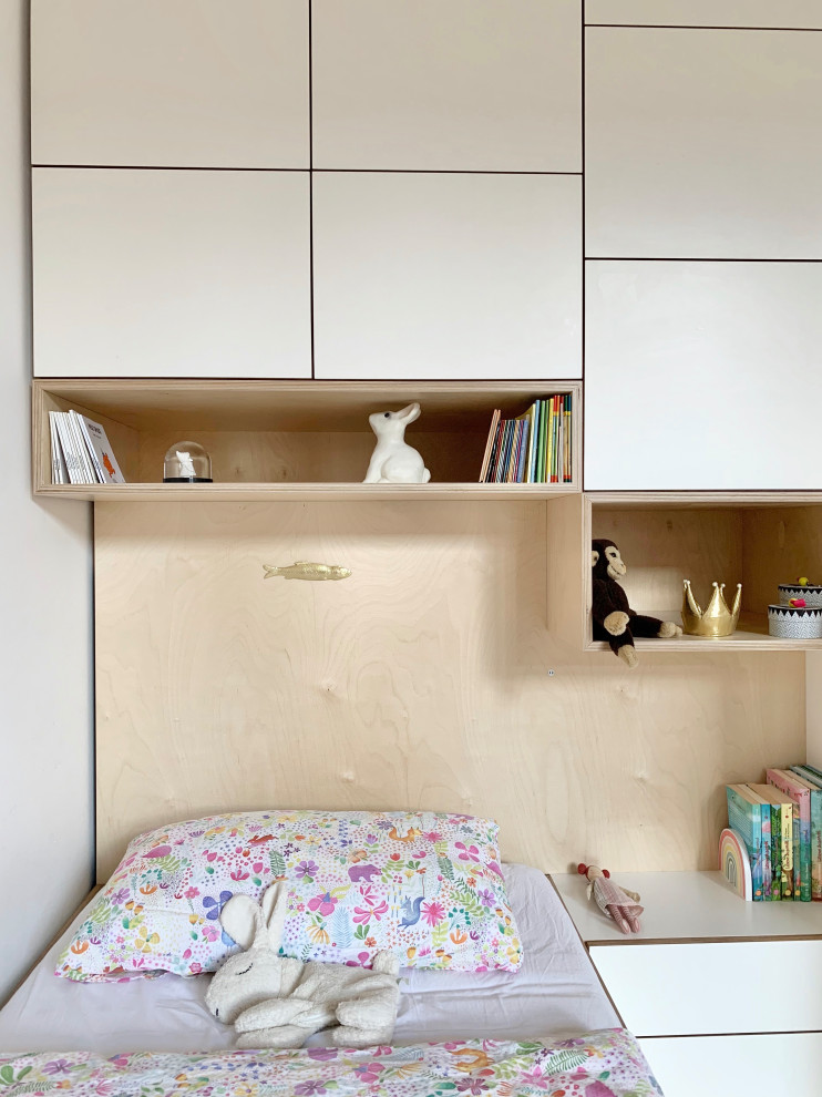 This is an example of a medium sized contemporary kids' bedroom for girls in Berlin with white walls, light hardwood flooring and brown floors.