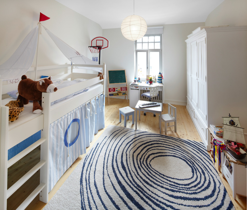 Nordisk inredning av ett stort pojkrum kombinerat med sovrum och för 4-10-åringar, med ljust trägolv och beige väggar