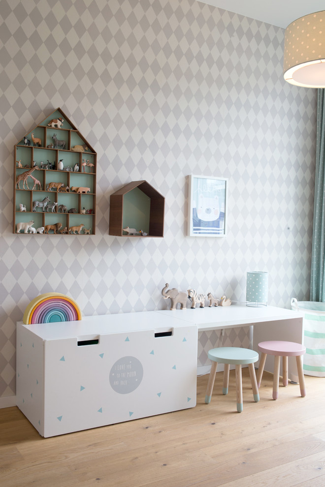 Cette image montre une chambre d'enfant de 1 à 3 ans nordique de taille moyenne avec un mur blanc, un sol en bois brun et un sol beige.