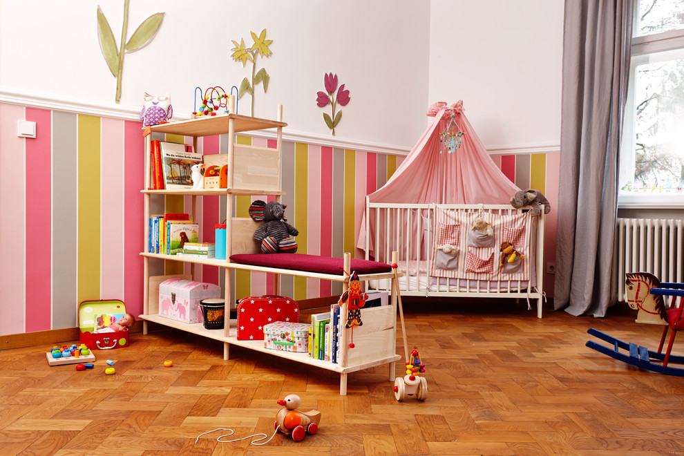 Cette image montre une chambre d'enfant de 4 à 10 ans nordique de taille moyenne avec un mur multicolore et un sol en bois brun.