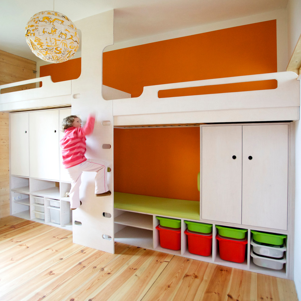 На фото: большая нейтральная детская в современном стиле с оранжевыми стенами, паркетным полом среднего тона и спальным местом для ребенка от 4 до 10 лет с