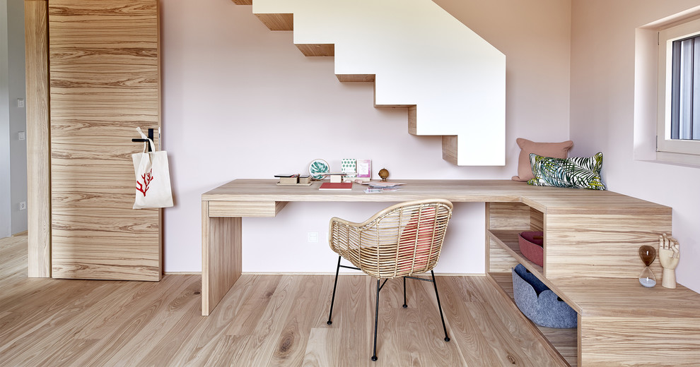 Aménagement d'une chambre d'enfant contemporaine de taille moyenne avec un bureau, un mur rose, un sol en bois brun et un sol marron.