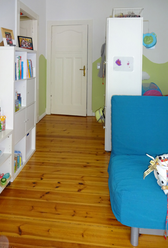 Modelo de dormitorio infantil de 1 a 3 años actual de tamaño medio con paredes verdes, suelo de madera oscura y suelo marrón