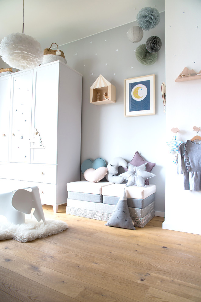 Ejemplo de dormitorio infantil de 1 a 3 años nórdico de tamaño medio con paredes grises, suelo de madera en tonos medios y suelo beige