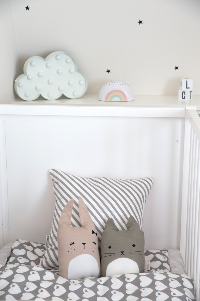 Inredning av ett minimalistiskt mellanstort könsneutralt småbarnsrum kombinerat med sovrum, med grå väggar, mellanmörkt trägolv och beiget golv