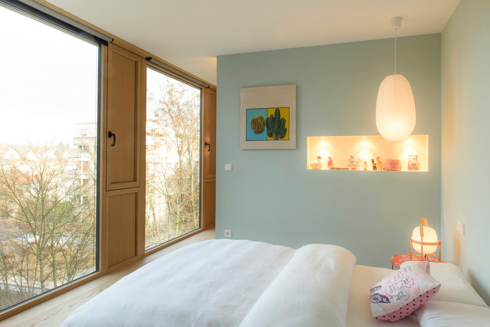 Medium sized contemporary children’s room for girls in Stuttgart with blue walls, light hardwood flooring and beige floors.