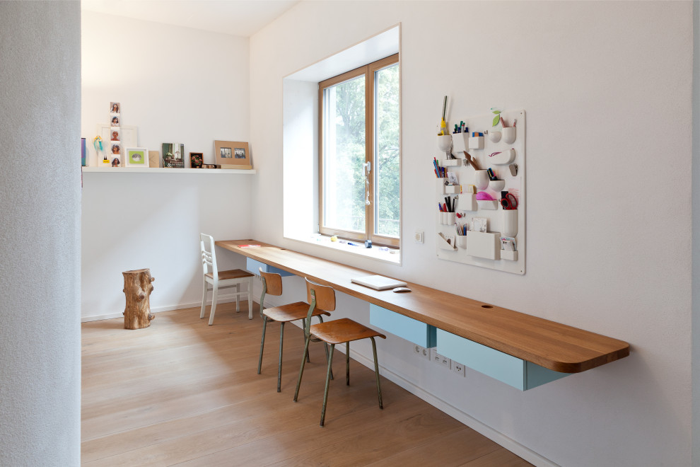 Idées déco pour une chambre neutre de 4 à 10 ans contemporaine avec un bureau, un mur blanc, un sol en bois brun et un sol marron.