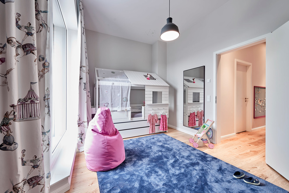 Cette image montre une chambre d'enfant de 4 à 10 ans design de taille moyenne avec un mur gris, un sol en bois brun et un sol marron.