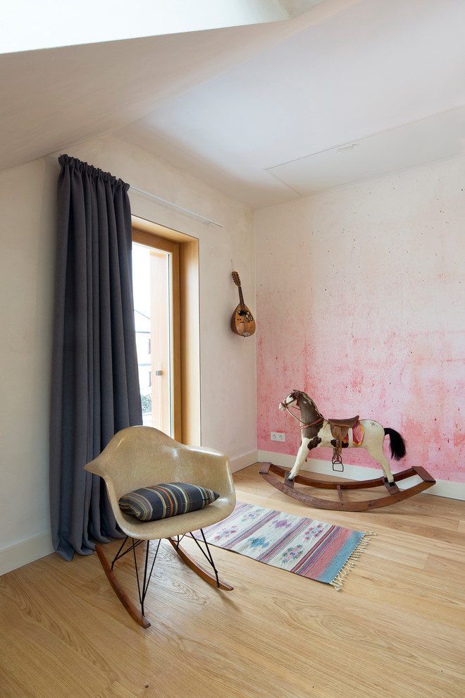 Inredning av ett skandinaviskt mycket stort könsneutralt barnrum kombinerat med lekrum, med vita väggar, ljust trägolv och brunt golv