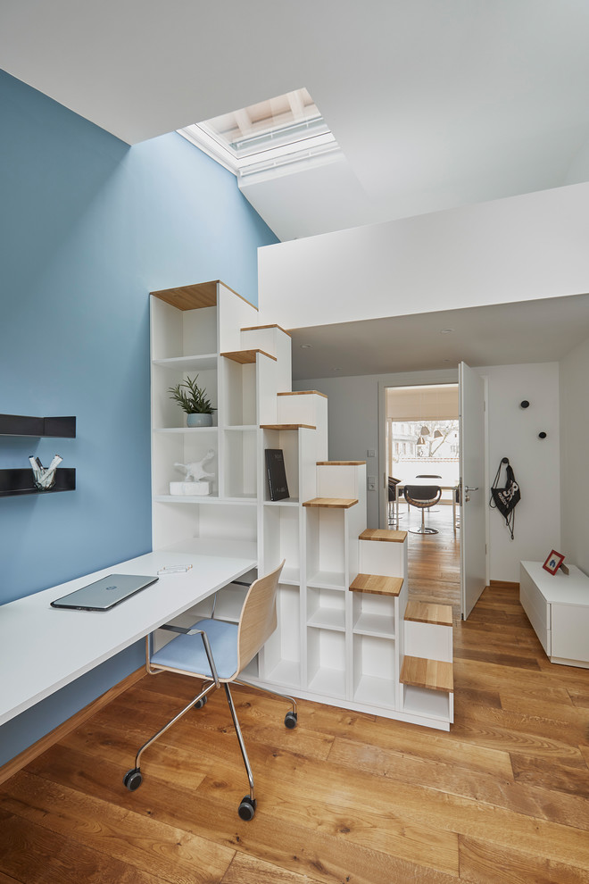 Aménagement d'une chambre d'enfant contemporaine de taille moyenne avec un bureau, un mur blanc, un sol en bois brun et un sol marron.