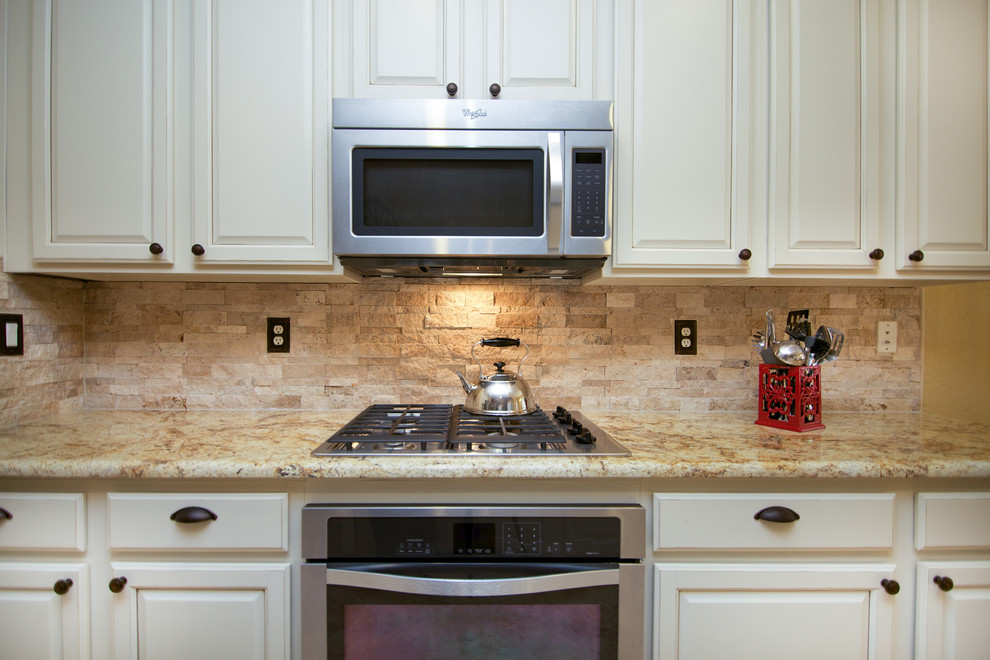 Immagine di una grande cucina country con lavello sottopiano, ante a filo, ante bianche, top in granito, paraspruzzi beige e elettrodomestici in acciaio inossidabile