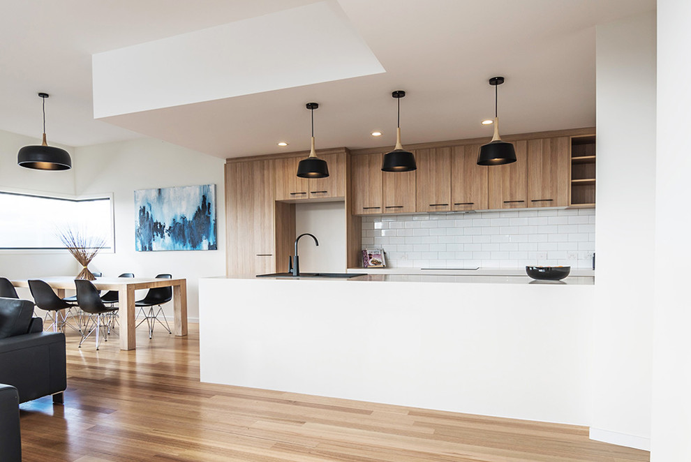 Inspiration for a medium sized contemporary galley kitchen/diner in Hobart with a single-bowl sink, flat-panel cabinets, light wood cabinets, laminate countertops, white splashback, stainless steel appliances, light hardwood flooring and an island.