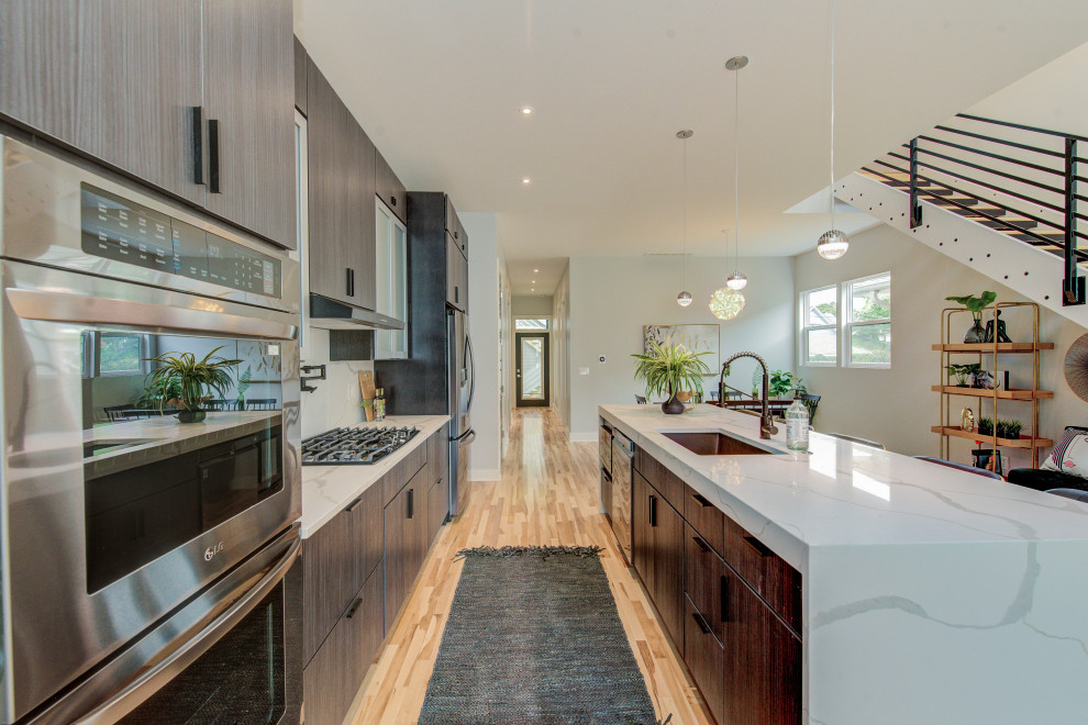 Example of a mid-sized trendy single-wall light wood floor and beige floor eat-in kitchen design in Indianapolis with a single-bowl sink, flat-panel cabinets, dark wood cabinets, marble countertops, white backsplash, marble backsplash, stainless steel appliances, an island and white countertops