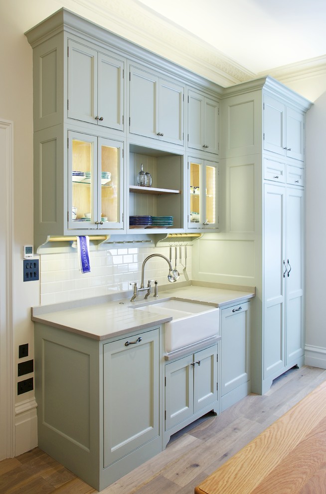This is an example of a medium sized traditional galley kitchen/diner in Surrey with a double-bowl sink, shaker cabinets, green cabinets, engineered stone countertops, ceramic splashback, medium hardwood flooring and an island.