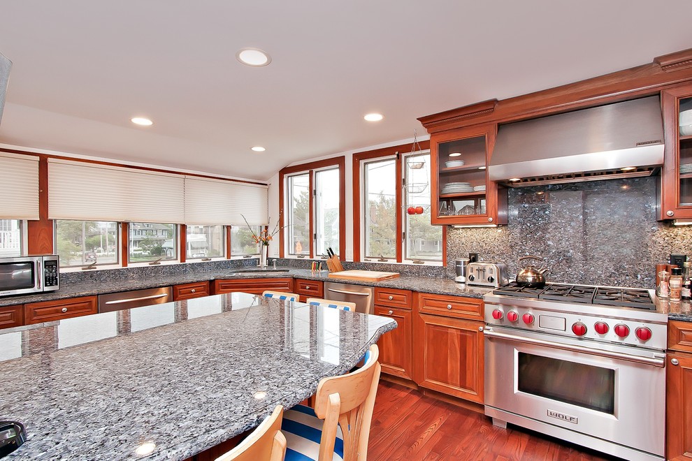 Immagine di una grande cucina costiera con lavello a doppia vasca, ante in legno scuro, top in granito, elettrodomestici in acciaio inossidabile e pavimento in legno massello medio