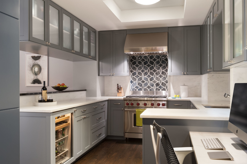 Inredning av ett modernt mellanstort kök, med en undermonterad diskho, luckor med infälld panel, grå skåp, marmorbänkskiva, stänkskydd i sten, integrerade vitvaror, mellanmörkt trägolv, grått stänkskydd, en halv köksö och brunt golv
