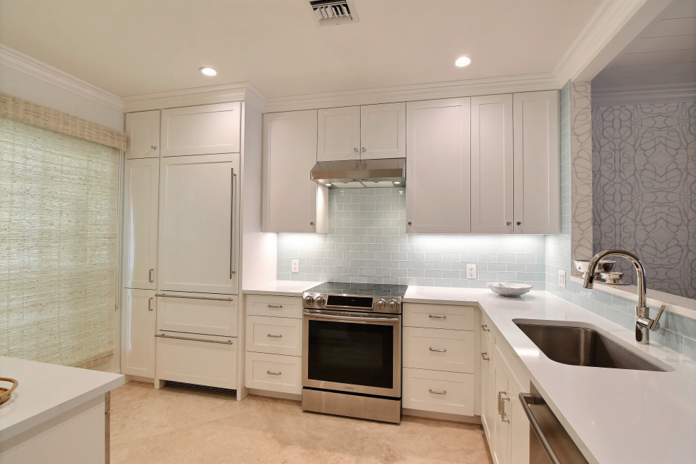 Design ideas for a small coastal galley kitchen in Miami with a single-bowl sink, shaker cabinets, white cabinets, engineered stone countertops, blue splashback, ceramic splashback, stainless steel appliances, travertine flooring, no island, beige floors and white worktops.