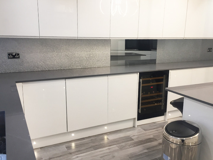 Example of a large minimalist eat-in kitchen design in Hertfordshire with flat-panel cabinets, white cabinets, marble countertops, gray backsplash, glass sheet backsplash and no island