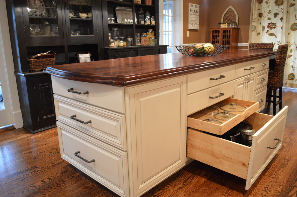 Example of a large classic l-shaped medium tone wood floor eat-in kitchen design in DC Metro with a farmhouse sink, raised-panel cabinets, white cabinets, wood countertops, beige backsplash, ceramic backsplash, stainless steel appliances and an island