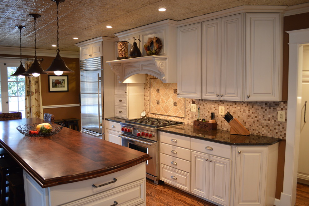 Klassisk inredning av ett stort kök, med en rustik diskho, luckor med upphöjd panel, vita skåp, träbänkskiva, beige stänkskydd, stänkskydd i keramik, rostfria vitvaror, mellanmörkt trägolv och en köksö