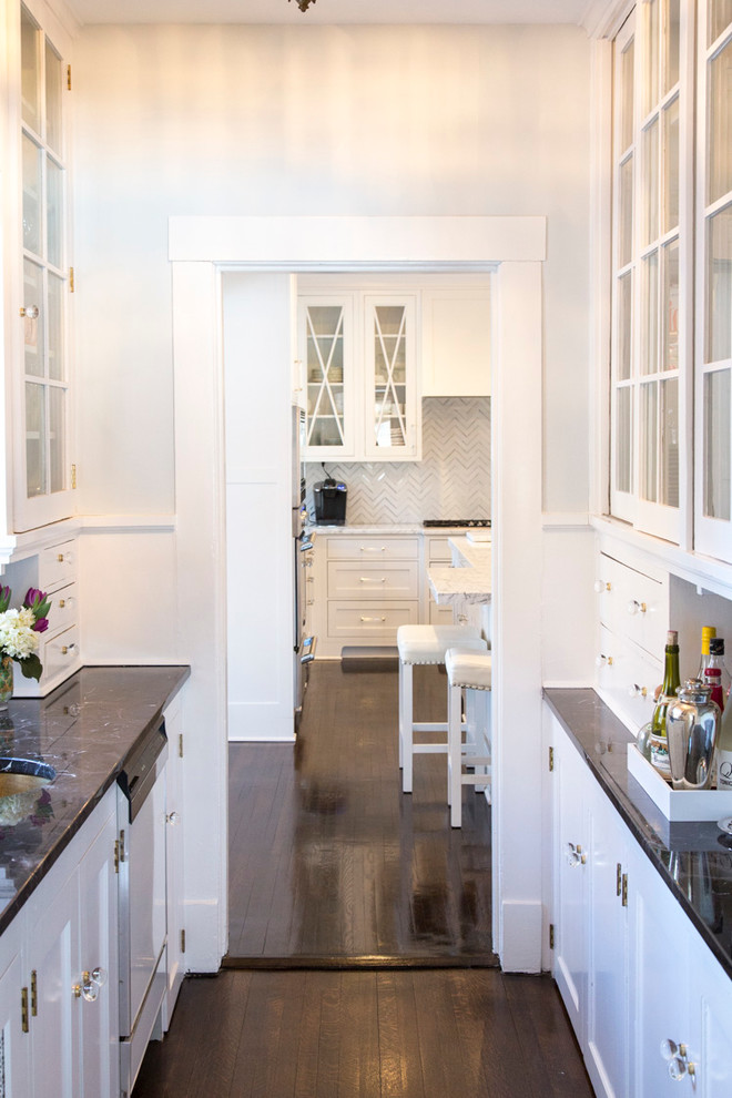 Eclectic enclosed kitchen in Cedar Rapids with a submerged sink, shaker cabinets, white cabinets, white splashback, integrated appliances, an island and brown floors.