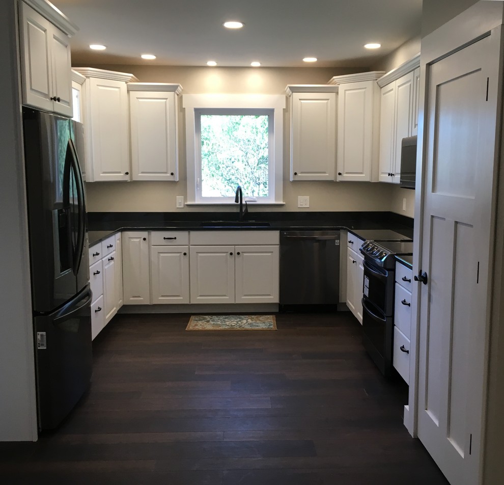 This is an example of a medium sized traditional u-shaped enclosed kitchen in Columbus with a submerged sink, raised-panel cabinets, white cabinets, granite worktops, black appliances, vinyl flooring, no island and brown floors.