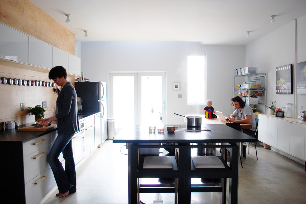На фото: кухня в стиле модернизм с плоскими фасадами, белыми фасадами и акцентной стеной